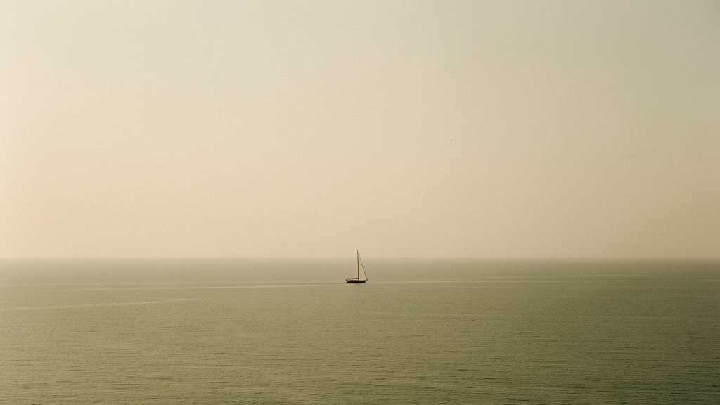 A solitary sailboat on a still, misted sea at first light — evoking the calm of a journey taken without friction